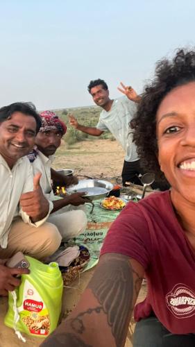 a group of men sitting around a table with food at Hostel Camel Castle & Safari in Jaisalmer