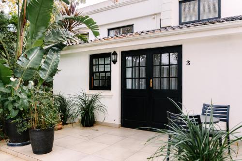 a black door on a white house with plants at The Salene Hotel & Apartments in Stellenbosch