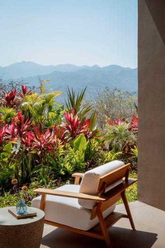 a bench with a book on it in front of flowers at One&Only Mandarina in Lo de Marcos