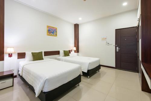 a hotel room with two beds and a television at Chokdee Place in Sakon Nakhon