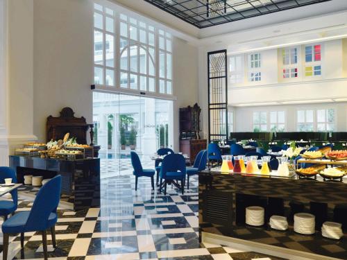 a restaurant with blue chairs and a table with food at Mövenpick Myth Hotel Patong Phuket in Patong Beach