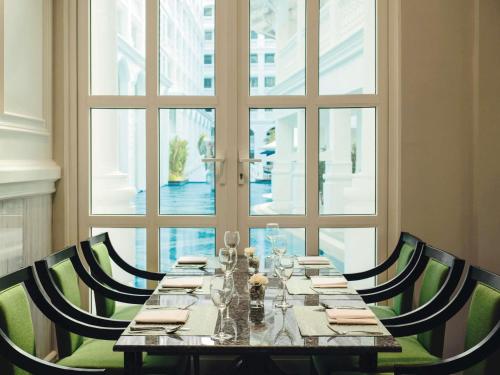 a dining room with a table and chairs and a window at Mövenpick Myth Hotel Patong Phuket in Patong Beach