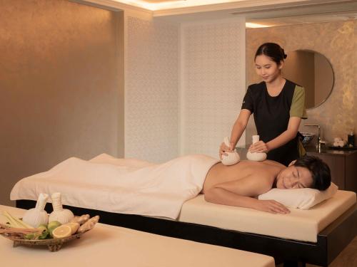 a woman giving a man a massage on a bed at Mövenpick Myth Hotel Patong Phuket in Patong Beach