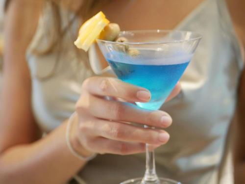a woman is holding a blue drink in a glass at Mövenpick Myth Hotel Patong Phuket in Patong Beach