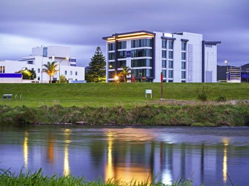 a building next to a river in front of a building at The Sebel Wellington Lower Hutt in Lower Hutt