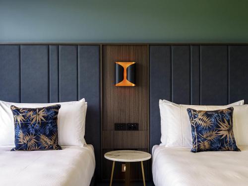 a hotel room with two beds and a table at The Sebel Wellington Lower Hutt in Lower Hutt