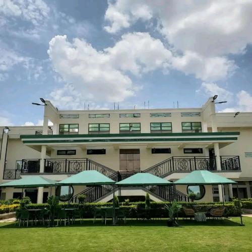 a large building with green umbrellas in front of it at Oodles garden in Nairobi