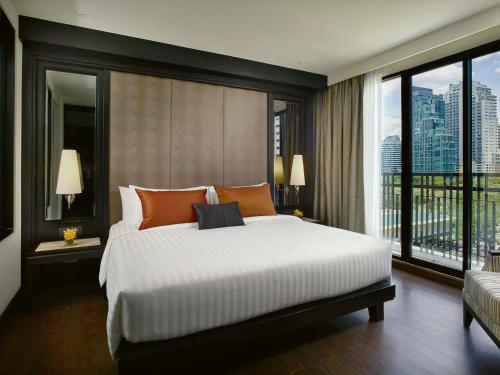 a bedroom with a large bed and a large window at Mövenpick Hotel Sukhumvit 15 Bangkok in Bangkok