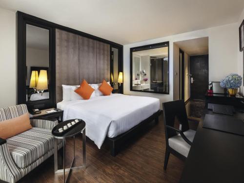 a hotel room with a bed and a couch at Mövenpick Hotel Sukhumvit 15 Bangkok in Bangkok