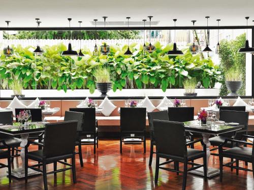 a restaurant with tables and chairs and plants at Mövenpick Hotel Sukhumvit 15 Bangkok in Bangkok