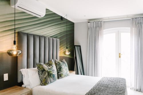 a bedroom with a bed with white sheets and pillows at The Salene Hotel & Apartments in Stellenbosch