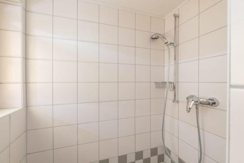 a shower in a bathroom with white tiles at Reisslerhof Hotel & Apartments - by myNests in Gröbming