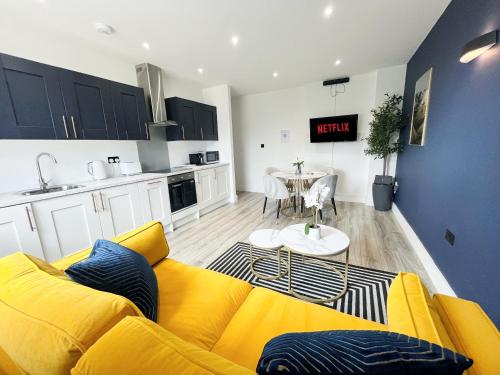 a living room with a yellow couch and a kitchen at Luxury Norwich City Centre Apartment - Free Parking in Norwich