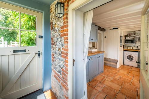 a kitchen with a brick wall and a door at Cockleshells in Castle Acre