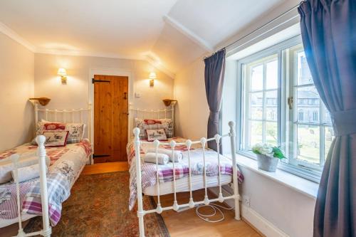 two beds in a room with a window at Cockleshells in Castle Acre