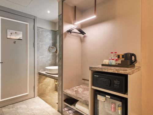 a bathroom with a sink and a microwave at Mercure Harbin Hexing Road in Harbin