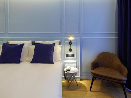 a bedroom with blue walls and a bed and a chair at Mercure Porto Centro Aliados in Porto
