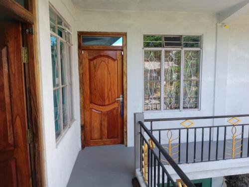 a porch with a wooden door and windows at Odyssey Stays Mawlynnong in Mawlynnong