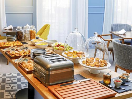 a table topped with plates of food and a toaster at Mercure Porto Centro Aliados in Porto
