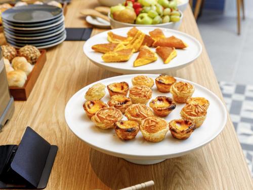 two plates of pastries and fruit on a table at Mercure Porto Centro Aliados in Porto