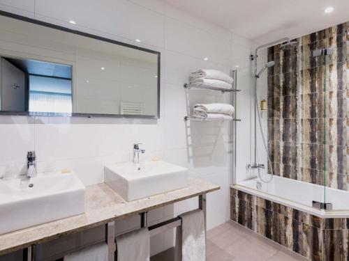 a white bathroom with two sinks and a shower at Mercure Bale Mulhouse Aeroport in Blotzheim