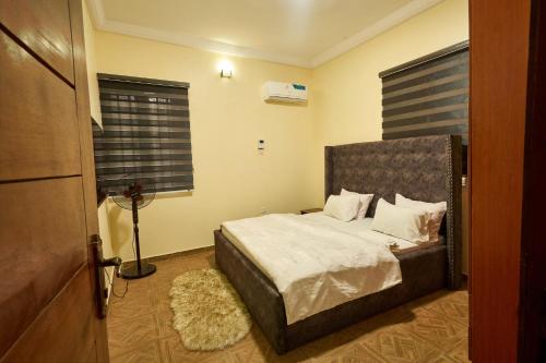 a bedroom with a bed with white sheets and a window at Shabi's Court in Lagos