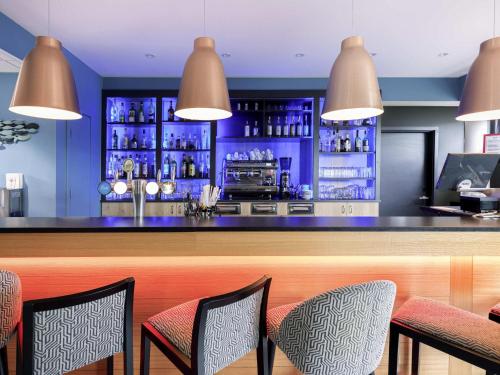 a bar in a restaurant with blue walls and chairs at Mercure Bale Mulhouse Aeroport in Blotzheim