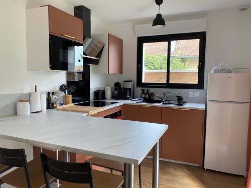 a kitchen with a white table and a white refrigerator at Le jardin de Sienne in Le Teich