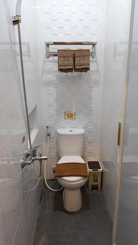 a small bathroom with a toilet with a shower at The Cabin Hotel Sidoarum in Sleman