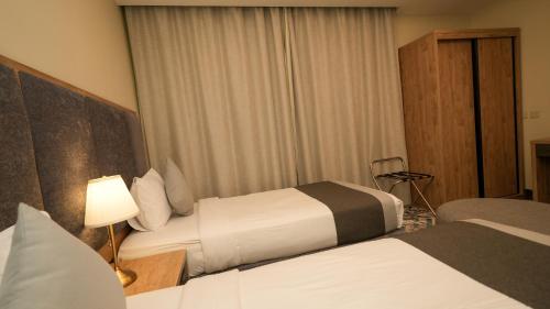 a hotel room with two beds and a lamp at بنزرت للشقق المخدومة in Al Hofuf