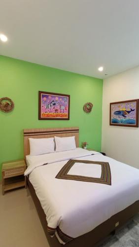 a bedroom with a large bed with green walls at The Cabin Hotel Sidoarum in Sleman