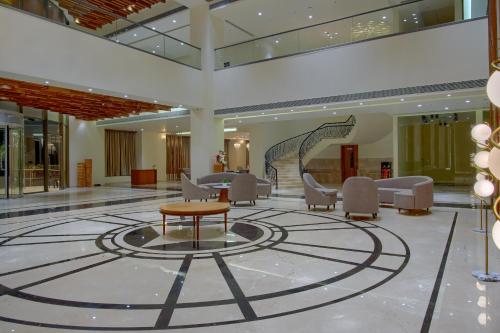 a lobby with a table and chairs in a building at DNT Plaza in Morbi