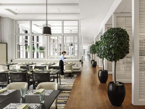 a woman standing in a restaurant with tables and chairs at Fairmont Wuhan in Wuhan