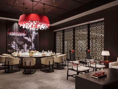 a dining room with a table and chairs and a red chandelier at Fairmont Wuhan in Wuhan