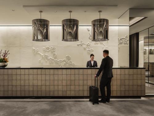 a man with a suitcase standing at a counter at Fairmont Wuhan in Wuhan