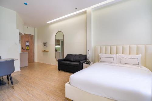 a bedroom with a white bed and a black chair at The Rixx Saigon Central - Next to Ben Thanh Market in Ho Chi Minh City