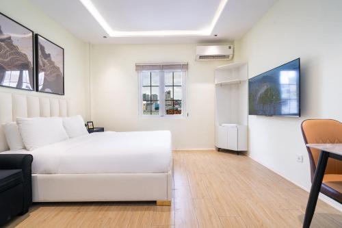 a white bedroom with a white bed and a table at The Rixx Saigon Central - Next to Ben Thanh Market in Ho Chi Minh City