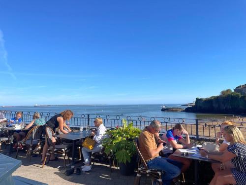a group of people sitting at tables by the water at EV friendly & Stylish Dunmore East Holiday Home Sleeps 7 in Dunmore East