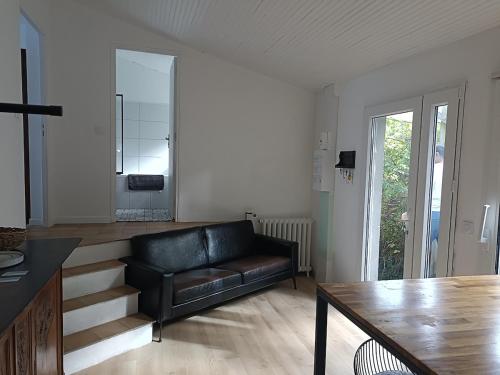 ein Wohnzimmer mit einer schwarzen Ledercouch und Treppe in der Unterkunft Boheme chic aux portes de Paris in Deuil-la-Barre