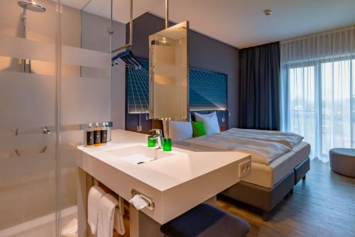 a hotel room with a sink and a bed at elaya hotel kevelaer in Kevelaer