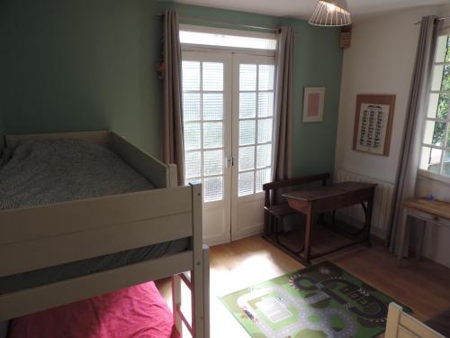a bedroom with a bed and a desk and a window at L'Opporak in Lindry