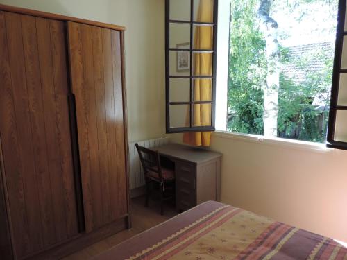 a bedroom with a bed and a desk and a window at L'Opporak in Lindry