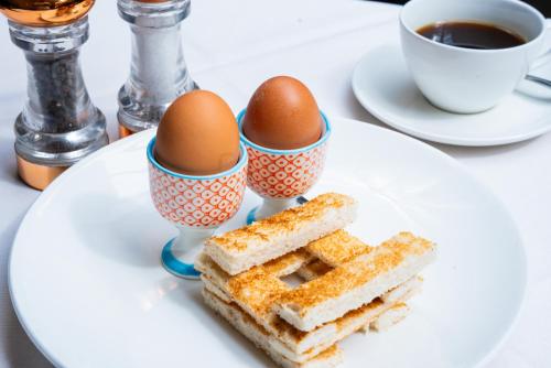 a plate with eggs and a sandwich and a cup of coffee at Lindeth Howe in Bowness-on-Windermere