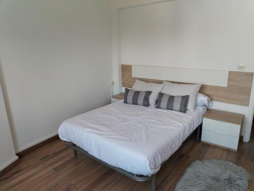 a small bedroom with a bed with white sheets and pillows at Apartamento en Carballiño in Carballino