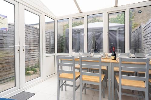 a dining room with windows and a table with a bottle of wine at Open Mind Property - 9 Guests & Free Parking in Portsmouth