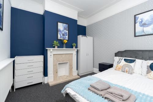 a bedroom with blue walls and a bed and a fireplace at Open Mind Property - 9 Guests & Free Parking in Portsmouth