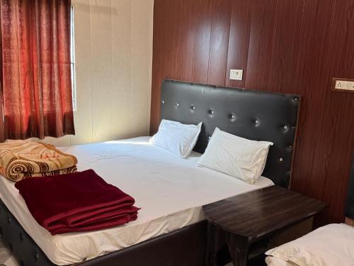a bedroom with a bed with a headboard and a table at Hotel Yash in Prayagraj