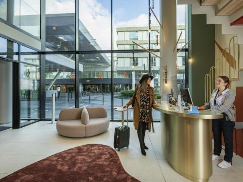 two women standing at a reception desk in a building at Adagio access Brussels Delta in Brussels