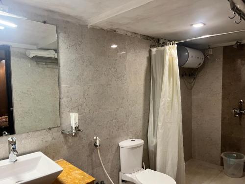 a bathroom with a toilet and a sink and a mirror at Breathing Earth - Rooms and Pool in Kolkata