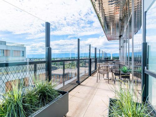 a balcony with tables and chairs on a building at Novotel Annemasse Centre - Porte de Genève in Annemasse